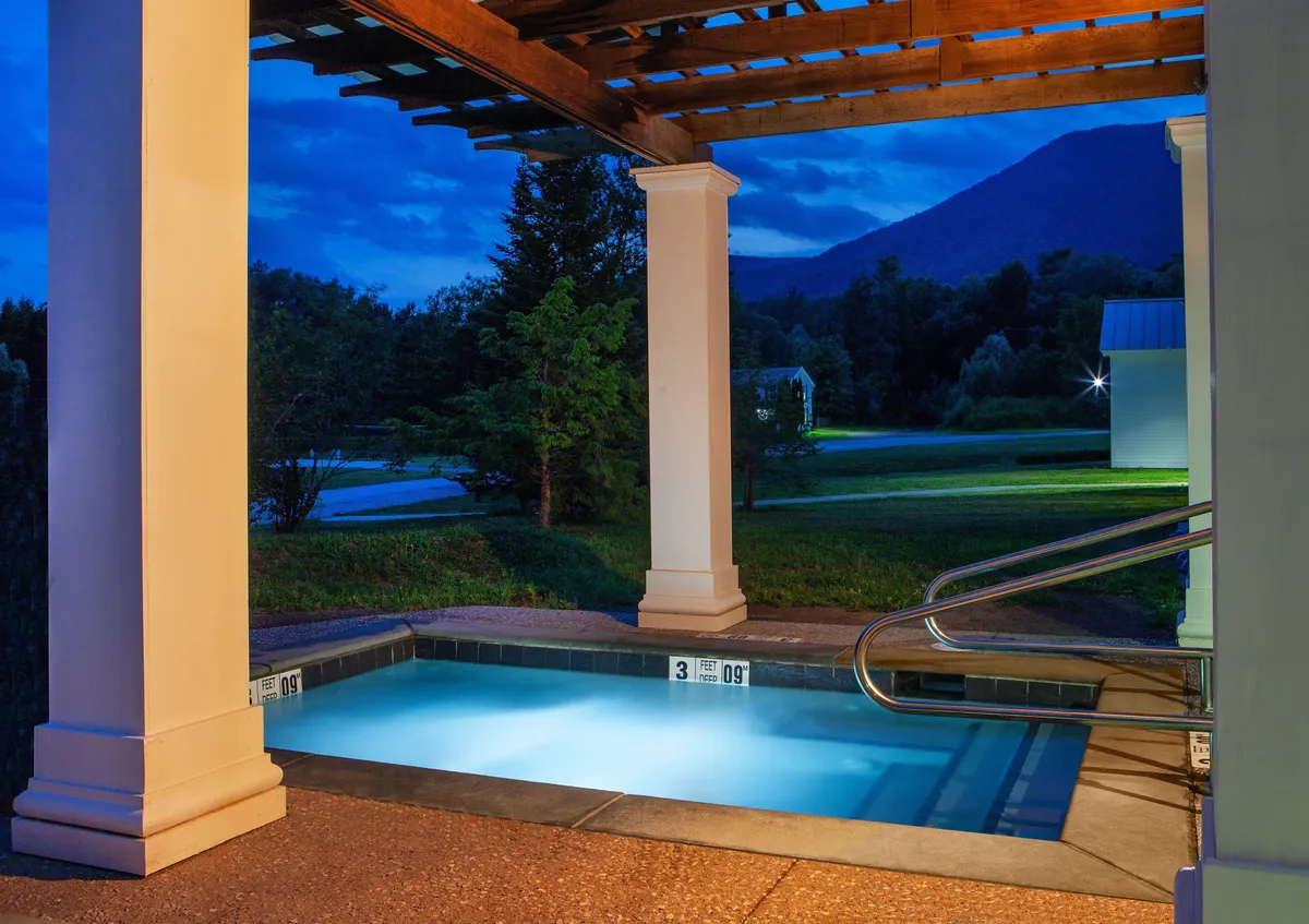 An inviting outdoor swimming pool framed by a stylish pergola, with a stunning mountain backdrop. The scene is peaceful, hinting at evening swims or stargazing sessions in a tranquil setting.